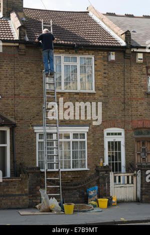 Man up a ladder fixing the roof Stock Photo