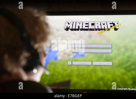 A teenage boy sits in front of his computer screen and plays the computer game Minecraft, developed by Swedish company Mojang Stock Photo