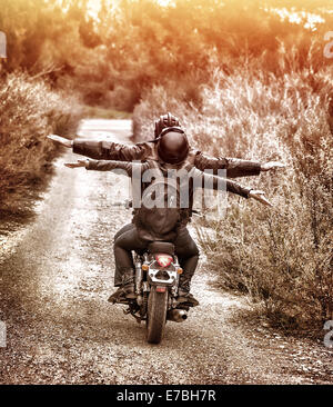 Vintage style image, rear view of two happy bikers riding on the road with raised up hands, active family enjoying journey Stock Photo