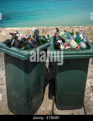 Discarded bottles of alcohol in dustbins by the sea. Stock Photo