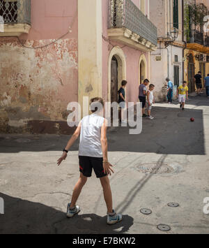Children playing football in the street in the old fishing town of Gallipoli, Puglia, Southern Italy. Stock Photo