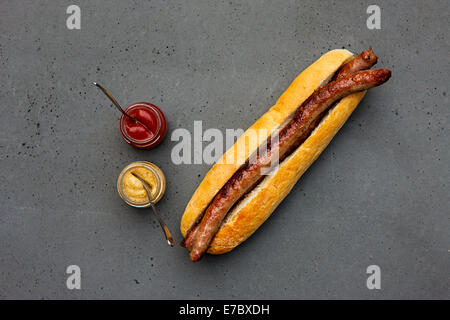 Modern classical hot dog with lamb sausage, bun, ketchup, mustard on concrete table