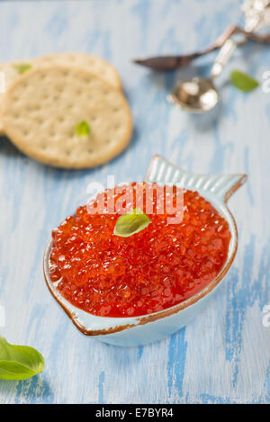 Red caviar in fish-shape bowl with crackers, closeup, selective focus Stock Photo