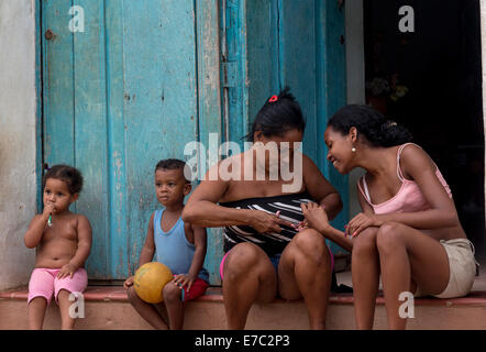 older woman manicuring a younger one on doorstep, Trinidad, Cuba Stock Photo