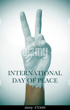 a man hand painted in white giving the V sign, as symbol of peace, and the sentence international day of peace Stock Photo