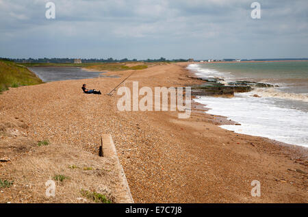 Man sea fishing from the shingle beach at East Lane, Bawdsey, Suffolk, England Stock Photo