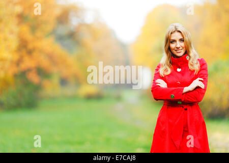 Young woman in red coat walking in autumn park Stock Photo