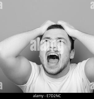 Portrait of angry man screaming and pulling hair - Monocrome or black and white portrait Stock Photo