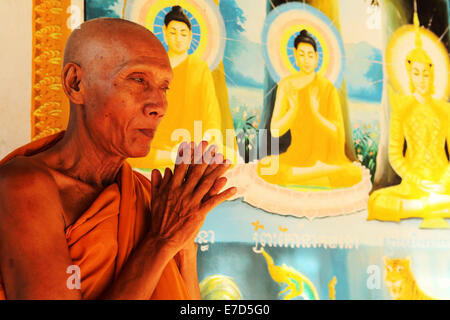 Buddhist monk praying by a colourful fresco at Angkor Wat in Siem Reap, Cambodia. Stock Photo