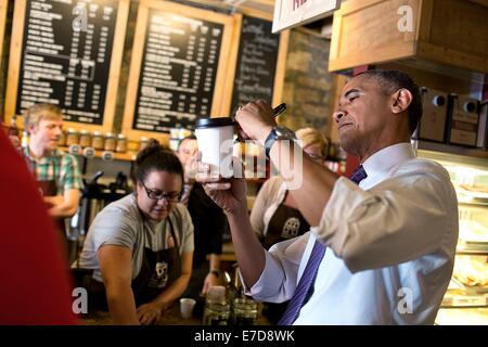 US President Barack Obama signs a coffee cup for a patron at Parkville Coffee July 30, 2014 in Parkville, Missouri. Stock Photo