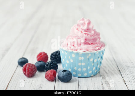 Fresh berries with whipped cream in paper cup on wooden background Stock Photo