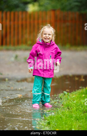 Happy little girl plays in a puddle Stock Photo