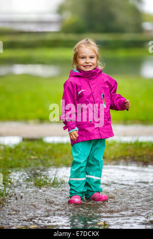 Happy little girl plays in a puddle Stock Photo