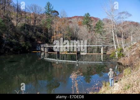 Fly fisherman casting on shore of Tuckasegee Lake and dam along scenic route NC 107 in mountains of SW North Carolina, USA Stock Photo
