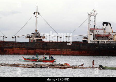 Manila, Philippines. 15th Sep, 2014. Fishermen stay on a boat by a cargo vessel swept by typhoon Kalmaegi near the Manila Bay in Manila, the Philippines, Sept. 15, 2014. Typhoon Kalmaegi (local name Luis) made a landfall in northern Philippines on Sunday afternoon and is expected to remain in the country until Tuesday, the state weather agency said. Credit:  Rouelle Umali/Xinhua/Alamy Live News Stock Photo