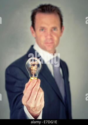 Businessman holding a lit lightbulb concept with the word Growth. Stock Photo