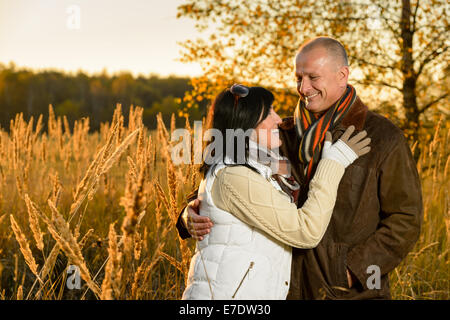 Couple in love hugging in autumn sunset countryside looking each other Stock Photo