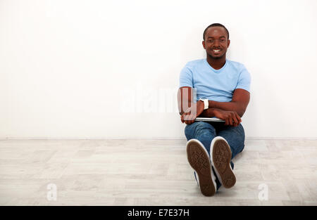 Portrait of a happy african man sitting with laptop on the floor Stock Photo