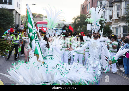 A couple dressed in green and white lead the procession holding hands and a flag. Stock Photo