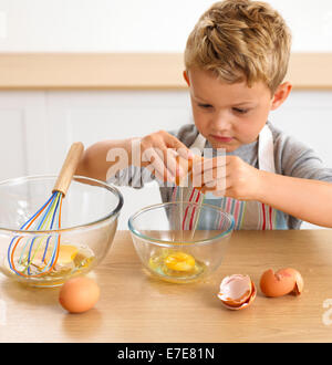 Boy cracking egg into bowl, 4 years Stock Photo