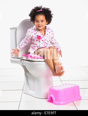 Baby girl using toilet seat Stock Photo