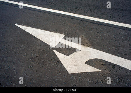 White line and painted arrows on black  tarmacadam. Stock Photo