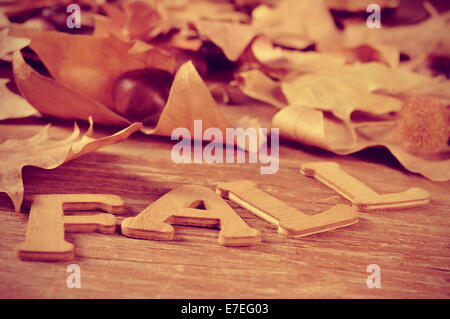 wooden letters forming the word fall and some autumn leaves on a weathered wooden background Stock Photo