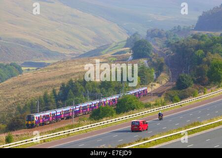 First Group Trans Pennine Express, Class 185 train passing the M6 motorway in the River Lune Valley. Howgills, Cumbria, UK. Stock Photo