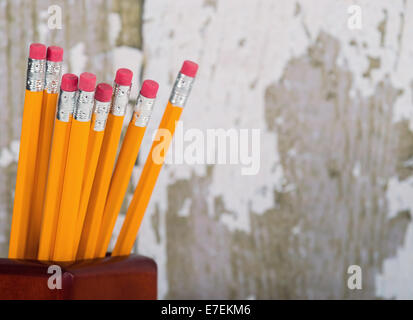 Group of eraser ends of yellow pencils in pencil holder. Gray wooden background with copy space Stock Photo