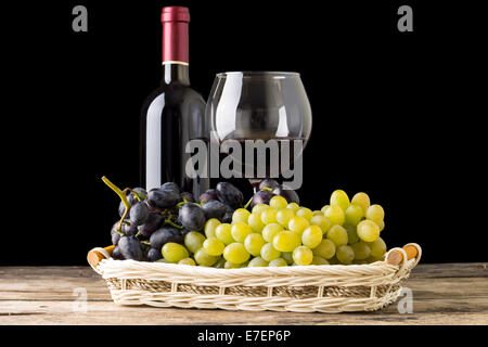 Winery still-life. Different varieties of grapes with wineglass and bottle of white wine on black background Stock Photo