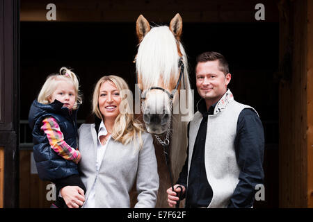 Young family standing with a Tyrolean Haflinger in front of a stall, North Tyrol, Austria Stock Photo