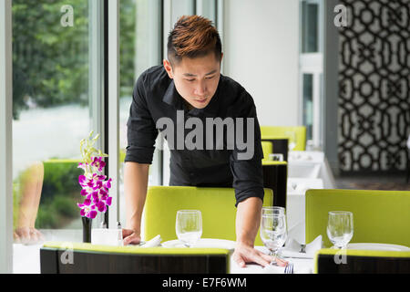 Asian waiter setting table in restaurant Stock Photo