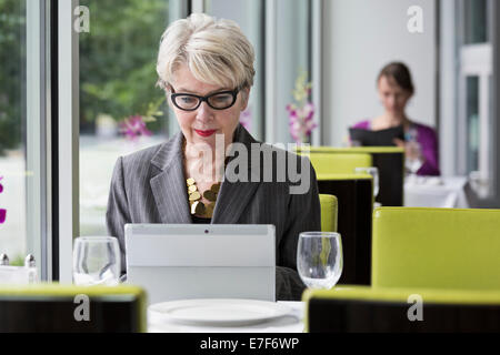 Caucasian businesswoman using tablet computer in restaurant Stock Photo