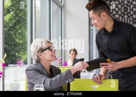 Businesswoman paying tab in restaurant Stock Photo