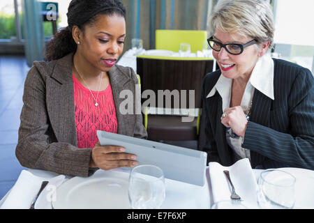 Businesswomen using tablet computer in restaurant Stock Photo