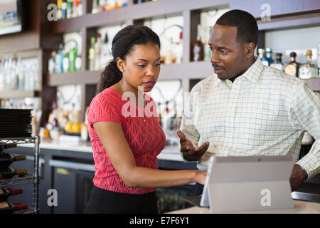 African American couple using tablet computer in restaurant Stock Photo