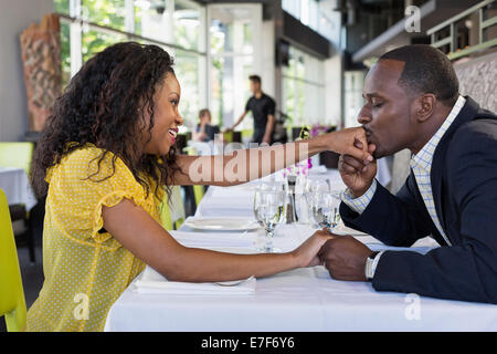 African American man kissing girlfriend's hand in restaurant Stock Photo