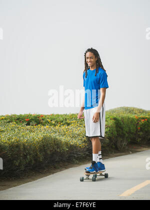 Black teenage boy riding skateboard on street Stock Photo