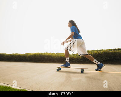 Black teenage boy riding skateboard on street Stock Photo