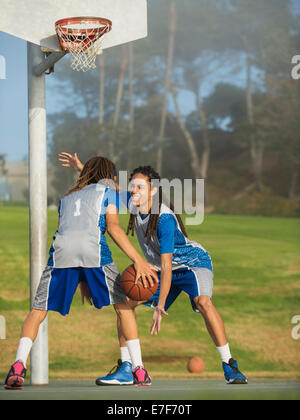 Black teenage boys playing basketball on court Stock Photo