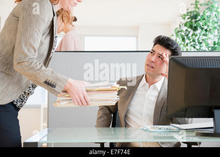 Businesswoman giving colleague stack of papers Stock Photo