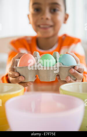 Mixed race boy dyeing Easter eggs Stock Photo