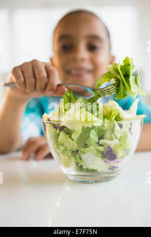 Mixed race boy eating salad Stock Photo