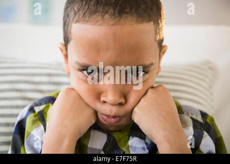 Mixed race boy pouting on sofa Stock Photo