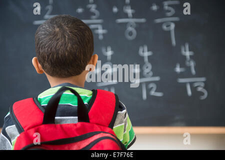 Mixed race boy doing math problems at board in class Stock Photo