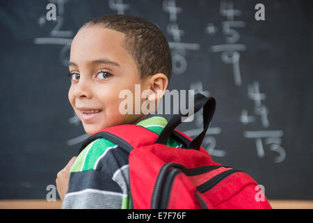 Mixed race boy doing math problems at board in class Stock Photo