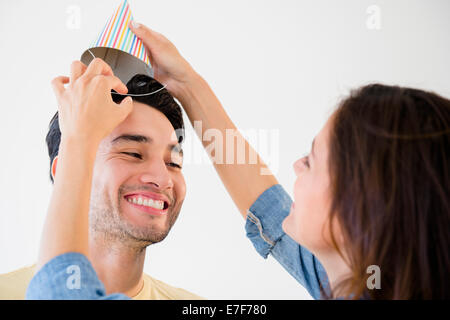 Woman putting party hat on boyfriend Stock Photo