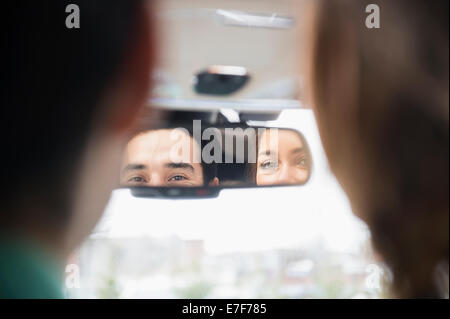 Couple admiring themselves in rearview mirror Stock Photo