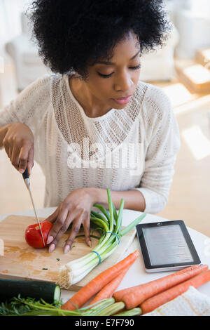 African American woman using tablet computer to cook Stock Photo