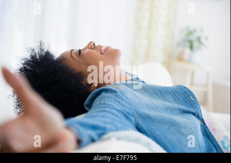 African American woman with arms outstretched on sofa Stock Photo